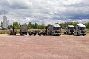 Photo: Some trucks and trailers parked on a large red gravel area